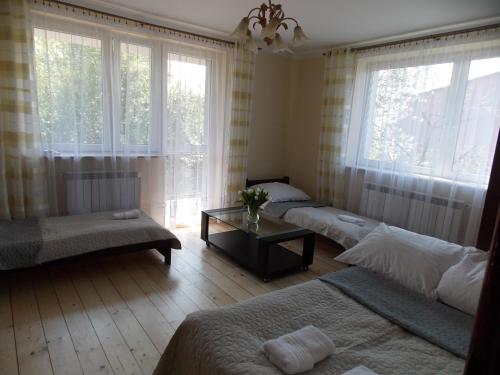 a bedroom with three beds and a table and windows at Noclegi Zator in Zator