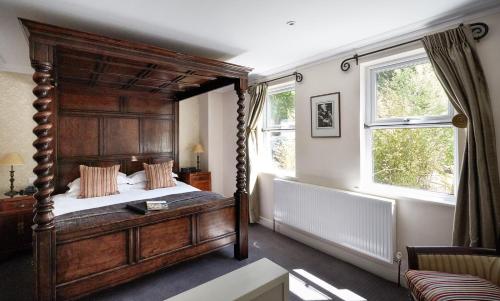 a bedroom with a large wooden bed and two windows at Dorian House Boutique B&B - Free Parking! in Bath