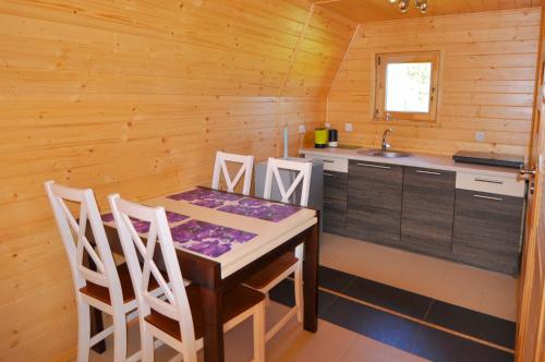 a kitchen with a table and chairs in a cabin at Ośrodek Daglezja in Kołczewo