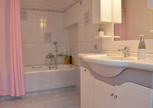 a bathroom with a sink and a tub with a shower at Kamari Beachfront Apartments in Xylokastro