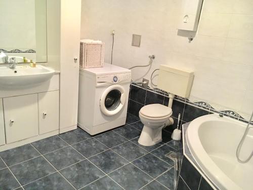 a bathroom with a toilet and a sink and a washing machine at Beach Apartment Lux View in Split