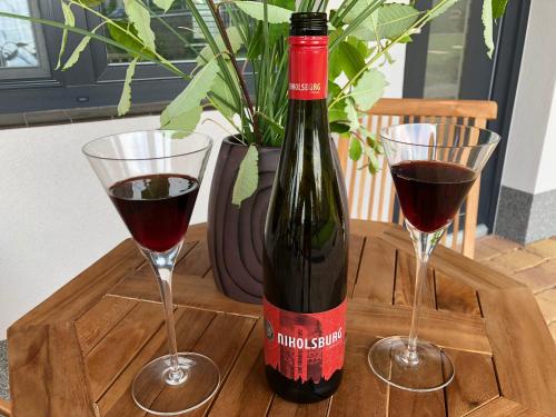 a bottle of wine and two glasses on a wooden tray at Apartmány Přítluky in Přítluky