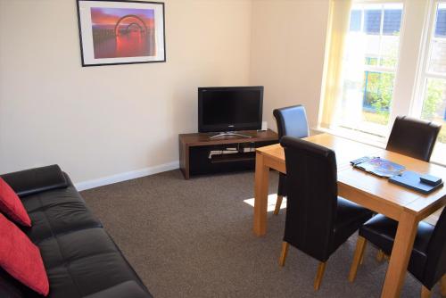 uma sala de estar com uma mesa e uma televisão em Kelpies Serviced Apartments Alexander- 2 Bedrooms em Falkirk
