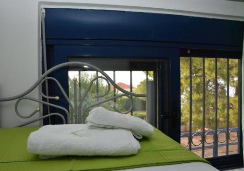 two towels sitting on a bed in front of a window at Kamari Beachfront Apartments in Xylokastro