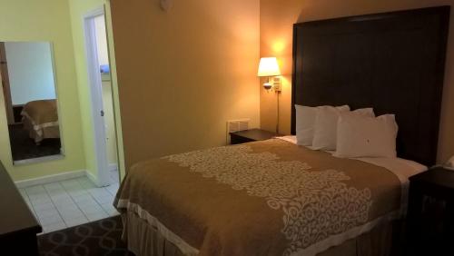 a hotel room with a large bed and a doorway at Days Inn & Suites by Wyndham Port Richey in Port Richey