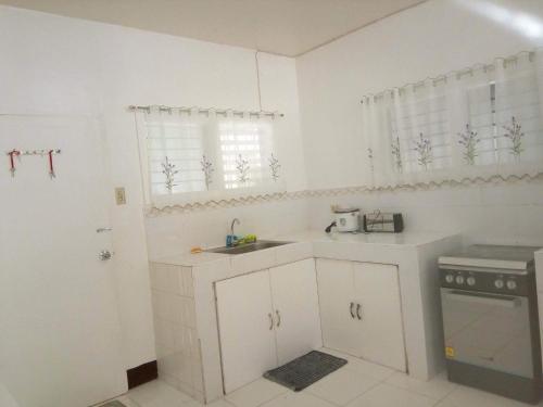 a white kitchen with a sink and a stove at Luna Oslob Travellers Inn in Oslob