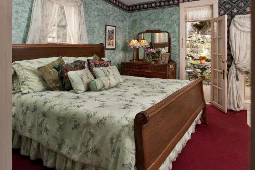 a bedroom with a large bed and a mirror at Cliff Cottage Inn, Downtown Bed & Breakfast in Eureka Springs