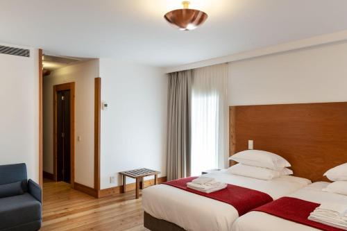 a hotel room with two beds and a blue chair at Casa de Santa Cruz in Felgar