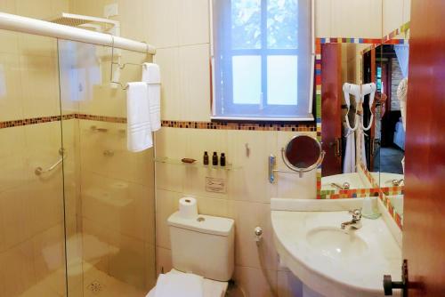 a bathroom with a toilet and a sink and a shower at Eliconial Paraty Pousada in Paraty