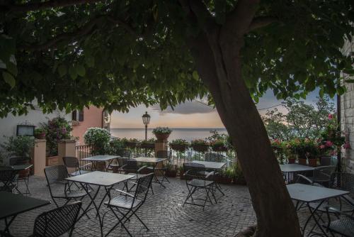 patio ze stołami, krzesłami i drzewem w obiekcie Locanda Rocco w mieście Sirolo