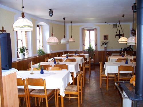 a restaurant with white tables and chairs and pendant lights at Hotel Krone in Gößweinstein