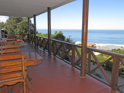 a balcony with benches and the ocean in the background at At Whale-Phin Guest House in Reebok