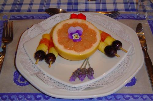 a plate of food with a grapefruit and other foods at At Whale-Phin Guest House in Reebok