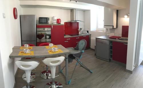 une cuisine avec des placards rouges et une table avec des tabourets dans l'établissement Côté chateau, à Carcassonne