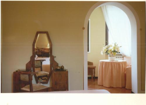 a room with a mirror and a chair and a table at Hotel Locanda Mel in Calolziocorte