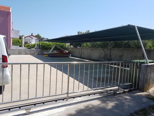 a fence with a black canopy over a parking lot at Villa Pino with Pool, Sauna & Jacuzzi in Petrcane