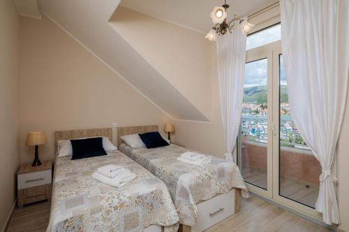 een slaapkamer met twee bedden en een groot raam bij Apartmani Oaza in Trogir