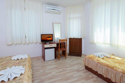 a hotel room with two beds and a desk with a television at Gloria Holiday House in Nesebar