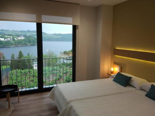 a bedroom with a bed and a large window with a view at Casona da Ponte in Portomarin