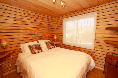 1 dormitorio con 1 cama en una cabaña de madera en Pupuya Vista Hermosa, en Navidad