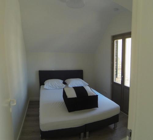 デ・パンネにあるons kotjeのベッドルーム1室(白いシーツ付きのベッド1台、窓付)