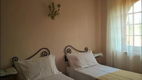 1 dormitorio con 2 camas con almohadas blancas y ventana en Villa Amalia Srls en Gizzeria
