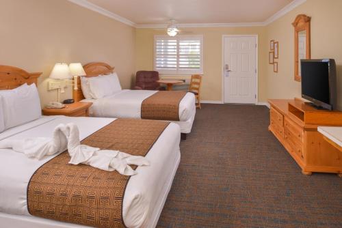 a hotel room with two beds and a flat screen tv at Cayucos Beach Inn in Cayucos