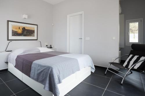 una camera bianca con un letto e una sedia di Villa Chez Julie a Citèra (Kýthira)