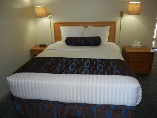 a large bed in a hotel room with a pillow on it at SlumberLodge Hotel in Penticton