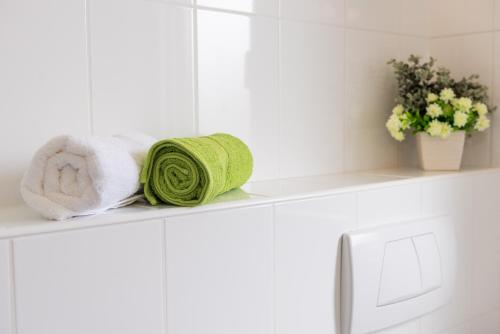 ブロダリツァにあるApartmani Nadaの白いバスルーム棚(タオル、花付)