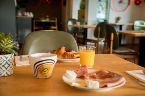 a table with a plate of food and a glass of orange juice at Hôtel Les Hauts de Meursault in Meursault