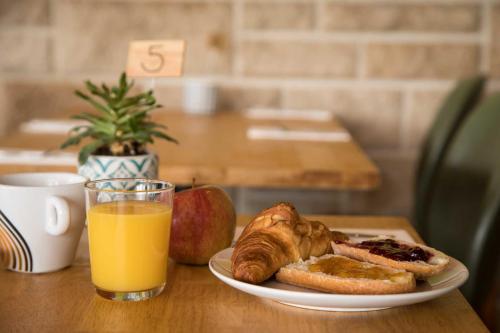 a plate of breakfast food and a glass of orange juice at Hôtel Les Hauts de Meursault in Meursault