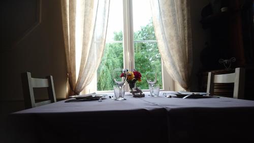 a table with a white table cloth and glasses on a window at Moulin d'Amour in Chambon