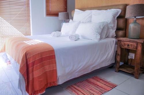 a bedroom with a bed with white sheets and pillows at Manhattan Suite-Canal Walk Mall in Cape Town