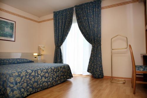 sypialnia z łóżkiem i dużym oknem w obiekcie Hotel Excelsior w mieście Monfalcone