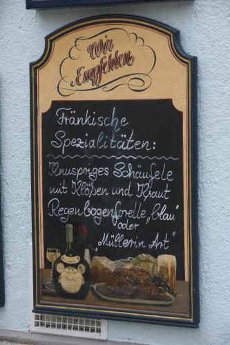 a sign on the side of a restaurant with a menu at Hotel Krone in Gößweinstein