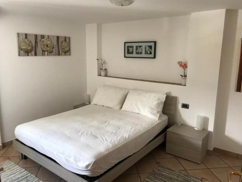 um quarto com uma cama com lençóis brancos em casa vacanze nicoletta em Aosta