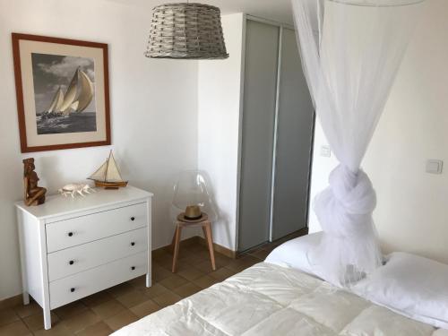 a bedroom with a bed and a dresser and a window at Port saint Louis du Rhône magnifique vue sur mer in Saint-Louis-du-Rhône