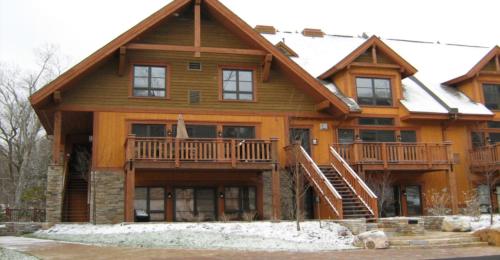 a large wooden house with snow on the ground at Étoile du Matin by Rendez-Vous Mont-Tremblant in Mont-Tremblant