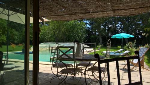 un patio avec une table, des chaises et un parasol dans l'établissement les trésors de malle mialle, au Thor