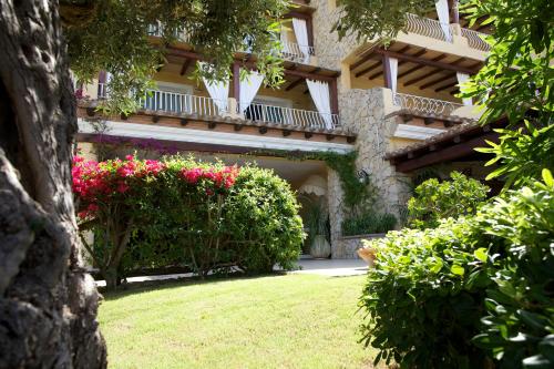 a building with a bunch of flowers in a yard at Boutique Hotel Su Sergenti in Villasimius