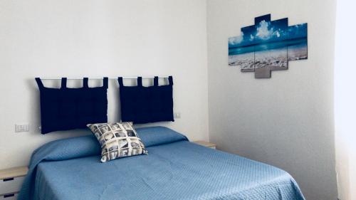 a bedroom with a blue bed and a picture on the wall at Veneto 29 in Alghero