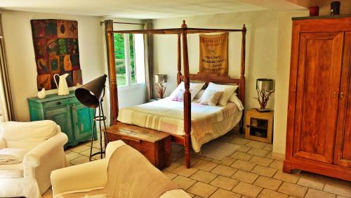 a bedroom with a four poster bed and a chair at les trésors de malle mialle in Le Thor