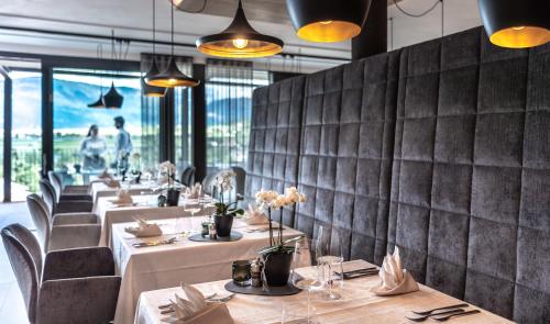 a restaurant with white tables and chairs and a wall of windows at Hotel Christof in Appiano sulla Strada del Vino