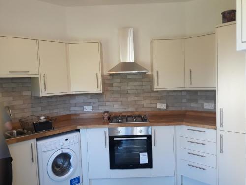 a kitchen with white cabinets and a washing machine at Kilreany in Sidmouth