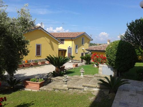 une maison jaune avec un jardin dans une cour dans l'établissement la Campagnola, à Cerveteri