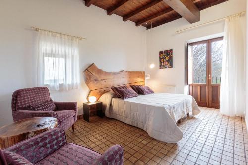 a bedroom with a bed and a chair and a window at Bosco Ciancio in Biancavilla