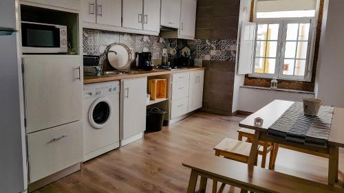 a kitchen with white cabinets and a table and a microwave at Casa do Arco Portalegre in Portalegre