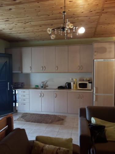 a kitchen with white cabinets and a couch in a room at Lefter's Cottege in Nea Irakleia