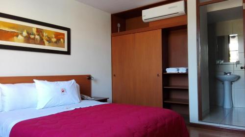 ein Schlafzimmer mit einem Bett mit einer roten Decke in der Unterkunft My Rouse Hotel in Chiclayo